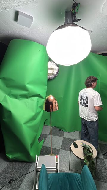 Le plateau de tournage en configuration fond vert : ballon diffusant en surplomb, boîte à lumière parabolique équipée d’un nid d’abeille, lampe d’appoint, fauteuils et guéridon.